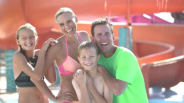 一家人带着两个孩子在水上乐园玩滑梯视频素材