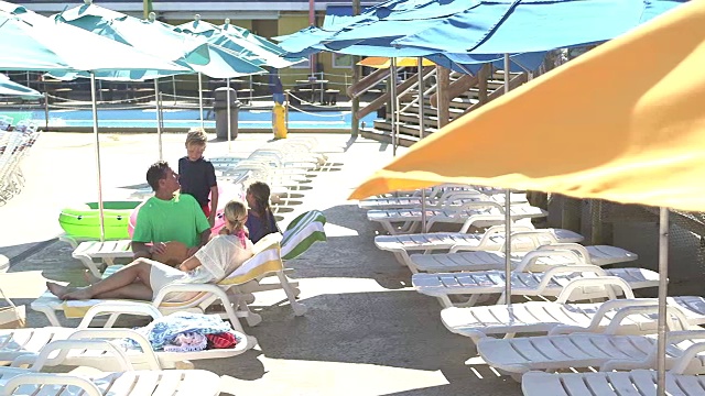 孩子和父母一起在泳池甲板上放松视频素材