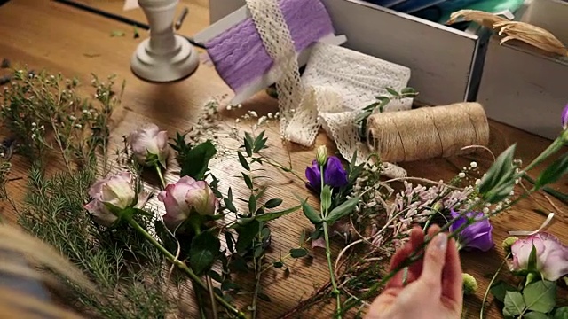 年轻女性金发花商准备花束。花店老板的手在她的花店制作花束。花店在花店剪花茎。Slowmotion拍摄视频下载
