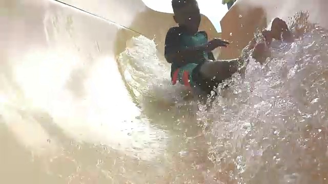 男孩在水上乐园滑下滑水道视频下载