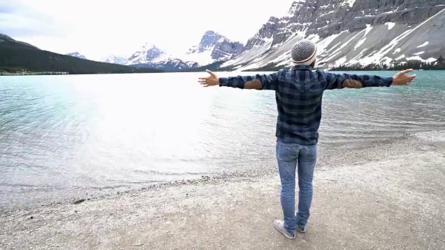男人站在湖边，张开双臂视频素材