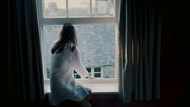 早上穿着睡袍坐在窗台上的女人视频素材