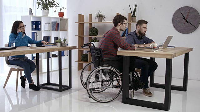 坐轮椅在办公室工作的嬉皮士视频下载