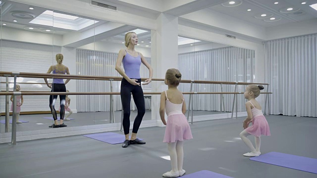 在芭蕾舞教室里，老师在镜子旁向孩子们展示舞蹈动作视频素材
