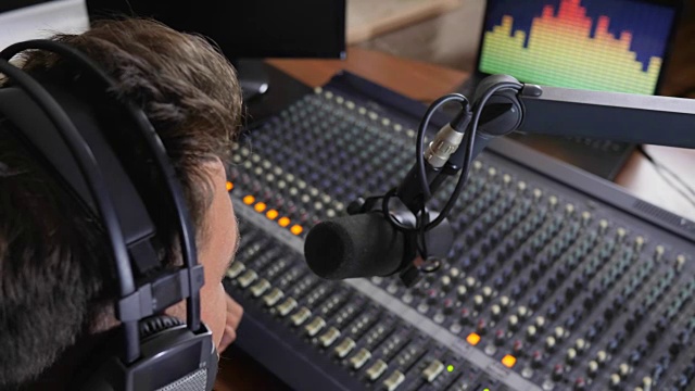 在电台工作时，一个戴着耳机的人对着麦克风说话视频下载