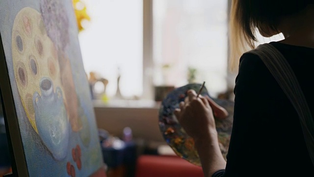 特写的女人艺术家混合颜料与刷子在调色板和绘画静物画之前在帆布在艺术工作室视频素材