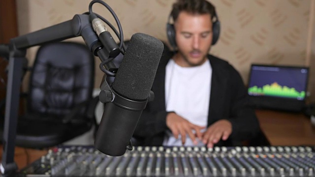 一名戴着耳机的男子在电台混音室前进入不聚焦的背景视频下载
