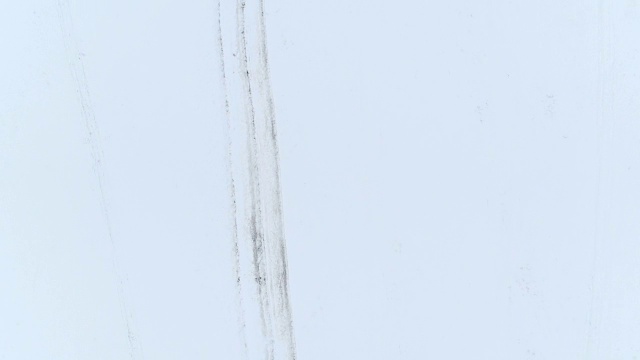4K天线:汽车轨道蜿蜒穿过白雪覆盖的田野视频素材