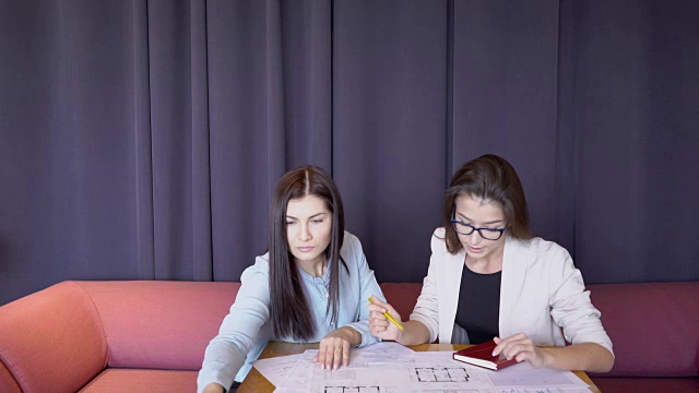 两个成年的商业妇女正在桌子上讨论一个绘画项目视频素材