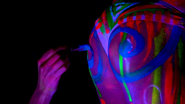 人体艺术画家把紫外线染料在美丽的年轻性感女孩的臀部。视频下载