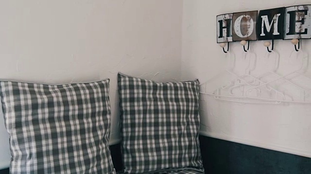 舒适的角落，格子枕头和一个可爱的时尚衣架在墙上写着一个舒适的家的名字视频下载