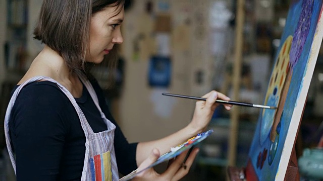 年轻的女艺术家在艺术学校的帆布上画静物画视频素材