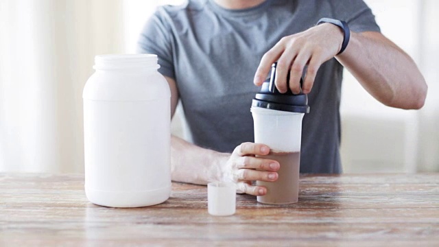 男人在健身跟踪器与罐子和瓶子准备蛋白质奶昔视频素材