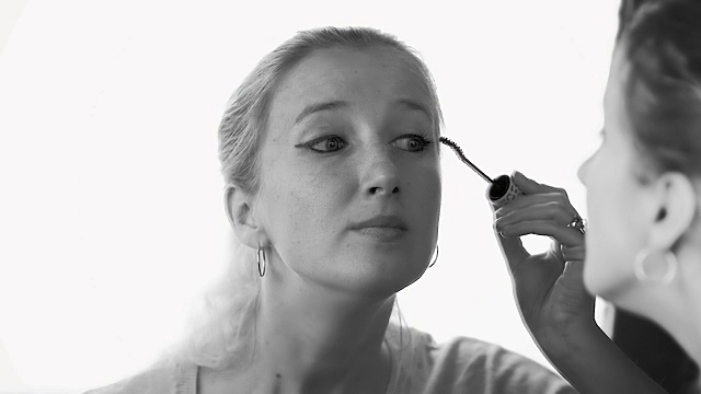 慢动作:一个美丽的年轻女孩的特写画睫毛与墨水看着镜子。视频下载