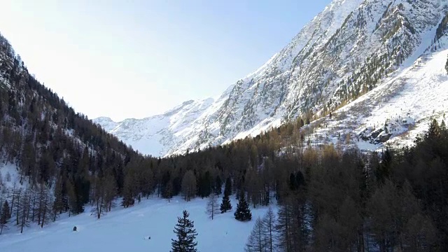 冬季无人机建立雪山下的森林森林山谷。雪山在户外自然。向前飞行。旅行探索阿尔卑斯山，4k俯视图视频视频素材