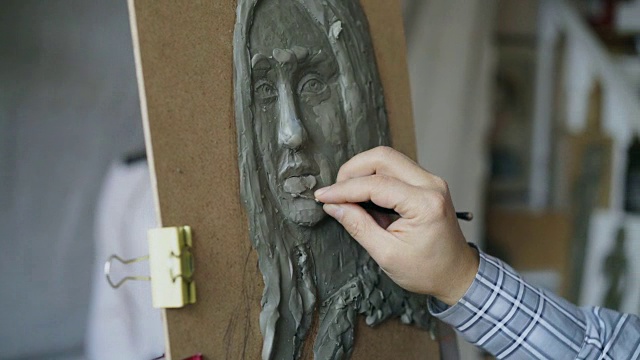 特写的雕塑家创造的雕塑的人的脸在画布上，而年轻女子摆姿势对他在艺术工作室视频下载