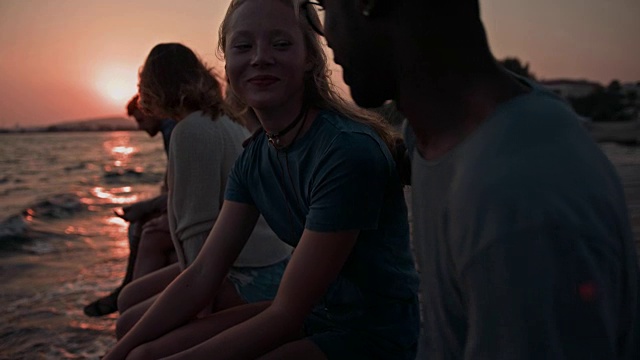 日落时分，年轻的多民族朋友和夫妇坐在码头上视频素材