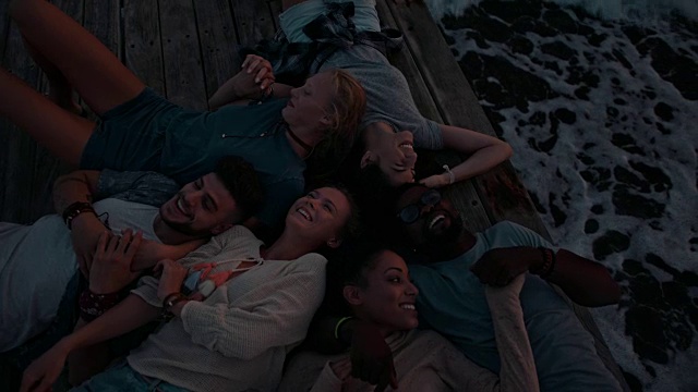 日落时分，年轻的多民族朋友们躺在码头上放松视频素材
