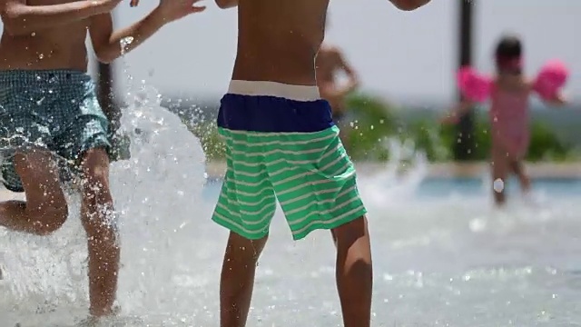 孩子们在暑假里享受游泳池。120帧/秒的慢镜头，孩子们在游泳池旁玩耍视频下载