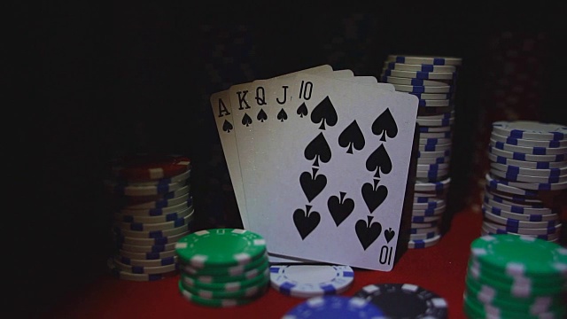 皇家同花顺牌和扑克筹码在红色的赌场桌上。视频下载