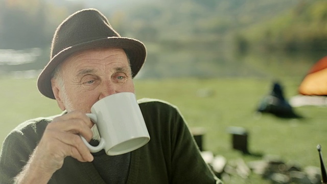 一个老人在湖边露营喝咖啡视频素材