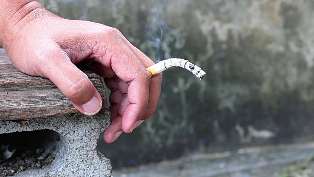 一个男人手里拿着香烟。特写一名男子手里拿着香烟。视频素材