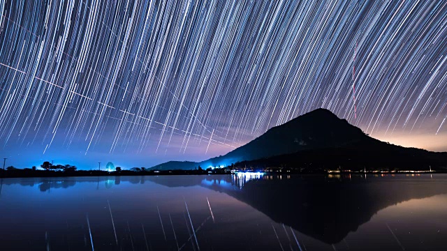 夜晚，星星的轨迹在山上和湖里移动。视频素材