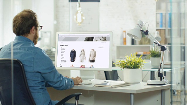 有才华的网页设计师使用个人电脑创建网站销售时尚服装的网上商店。他在一家现代创意工作室工作。视频素材
