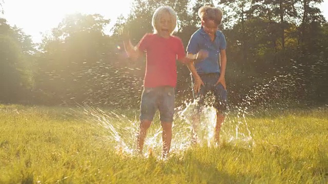 两个孩子跳进水坑里溅起水花视频下载