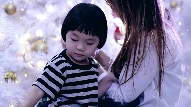 年轻的母亲和女婴使用智能手机和享受在圣诞节视频下载