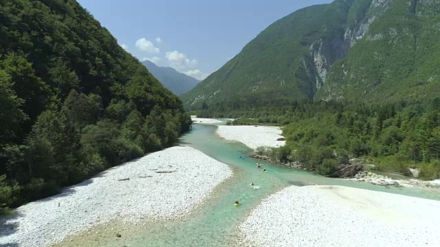 航拍:皮划艇在美丽清澈的绿色河流中滑行穿过山谷。视频素材