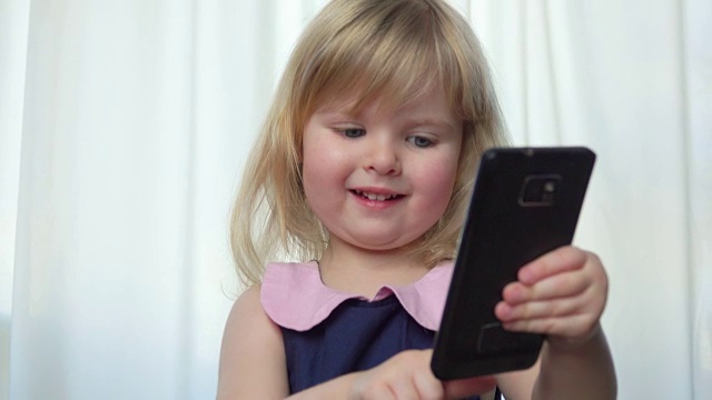 漂亮的蓝眼睛女孩翻阅着手机上的照片视频下载