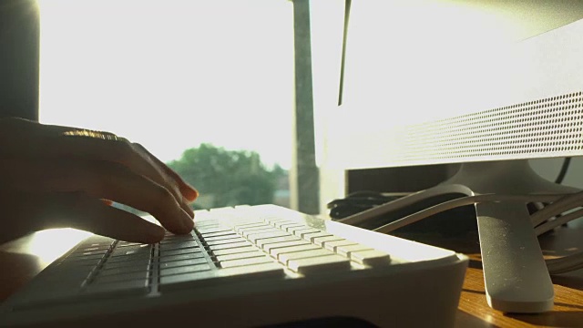 一个年轻女子在一张桌子前用电脑键盘工作。视频素材
