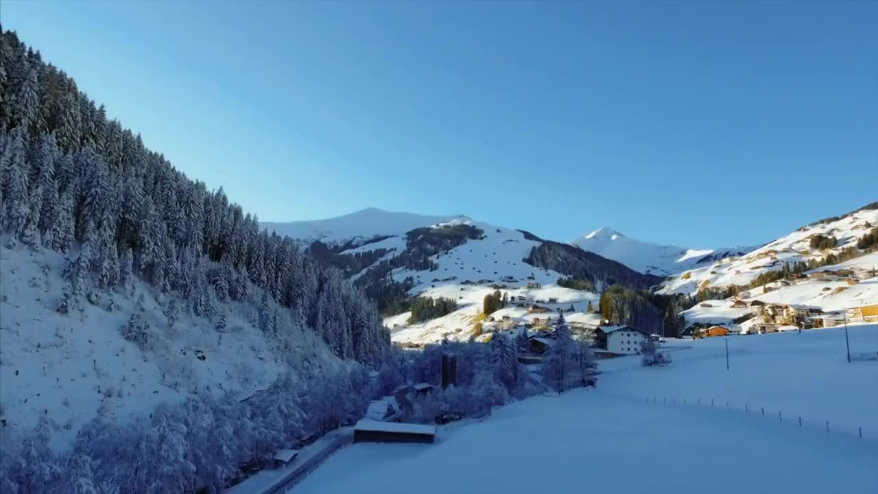 一架美丽的无人机拍下了瑞士寒冷的景色。镜头升起，映入眼帘的是一个小山村，坐落在阿尔卑斯山冬日寒冷的阳光下。视频素材