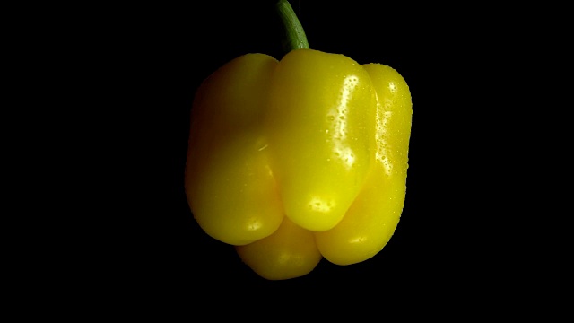 特写旋转新鲜的黄色胡椒在黑色的背景。视频素材