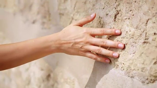 女人的手在古老的石墙上移动。滑动。性感动人。坚硬的石头表面视频素材