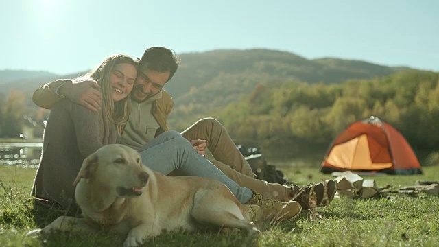 一对年轻夫妇在湖边和他们的狗玩耍视频下载