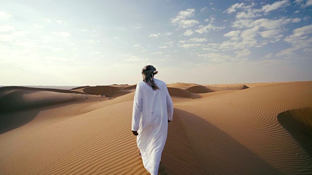 中东人在沙漠的沙丘上行走视频素材