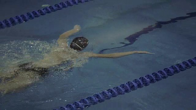 戴泳镜的女子游泳者在水里蛙泳视频素材