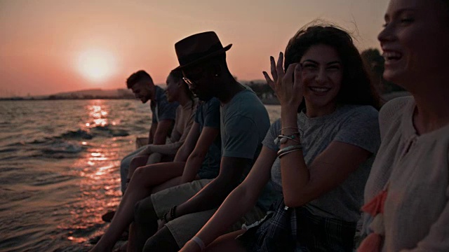 年轻的多民族潮人朋友们在暑假坐在码头上视频素材