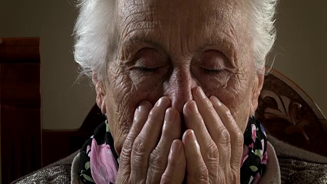 悲伤和沮丧的老年妇女把她的手放在她的脸视频素材
