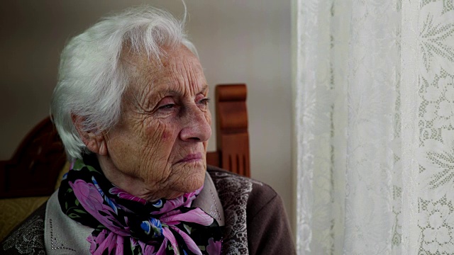 愁眉苦脸的老妇人望着窗外视频素材