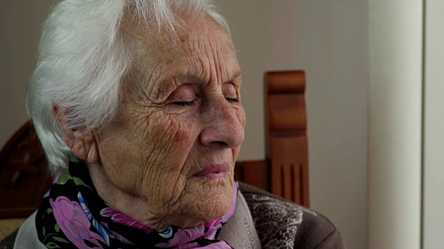 坐在窗边的悲伤而忧郁的老妇人视频素材