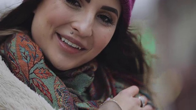 在一个城市里，戴着紫色帽子的年轻快乐的女人抬头对着镜头微笑视频下载
