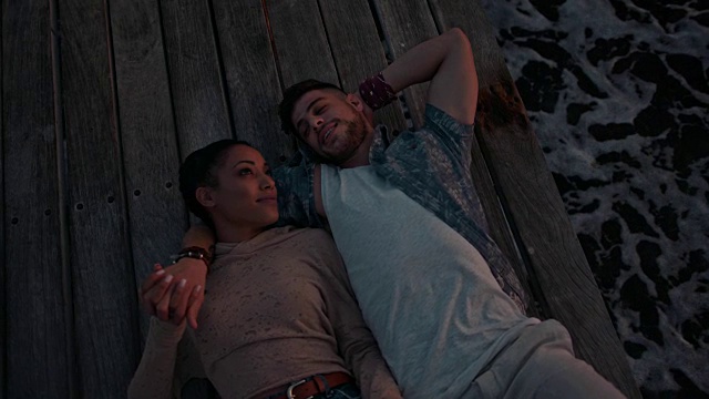 年轻浪漫的多民族夫妇放松在木码头在日落视频素材