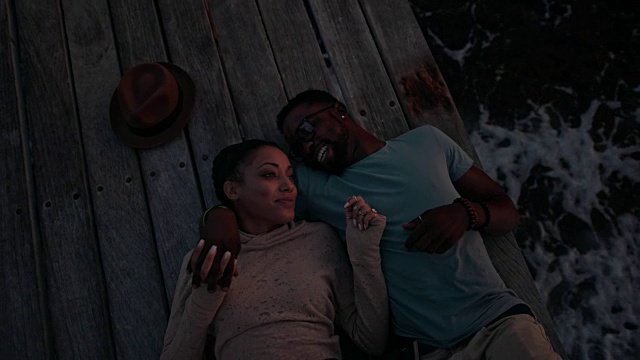 年轻浪漫的多民族嬉皮士夫妇调情躺在码头上视频素材