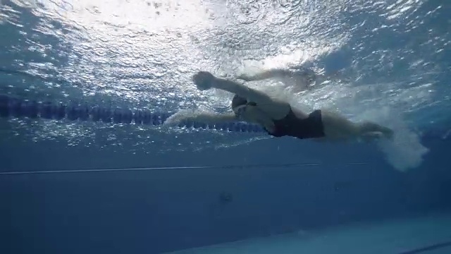 运动女子游泳蝶泳在蓝色的水池水下视图视频素材