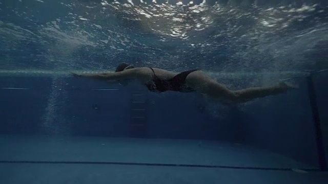 运动女子游泳者在水下转弯和浮动蝶式游泳池视频素材