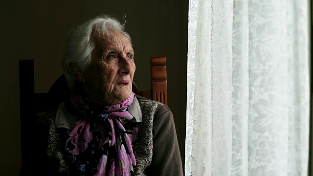 坐在窗边的悲伤而忧郁的老妇人视频素材
