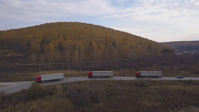 货车和汽车行驶在郊区的道路上，背景是秋天的森林视频下载